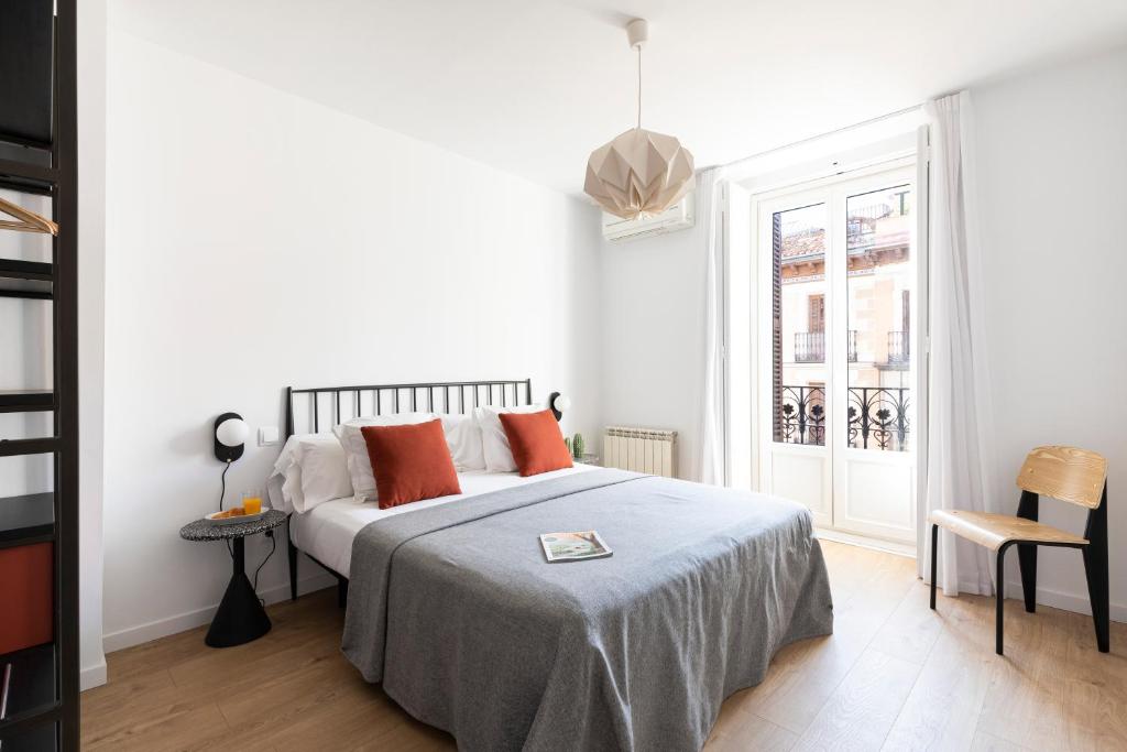 a white bedroom with a bed and a window at Aspasios Calle Mayor Apartments in Madrid