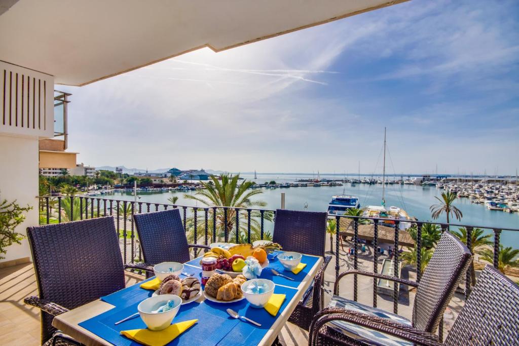 una mesa con comida en el balcón con vistas al puerto en Concha en Port d'Alcudia