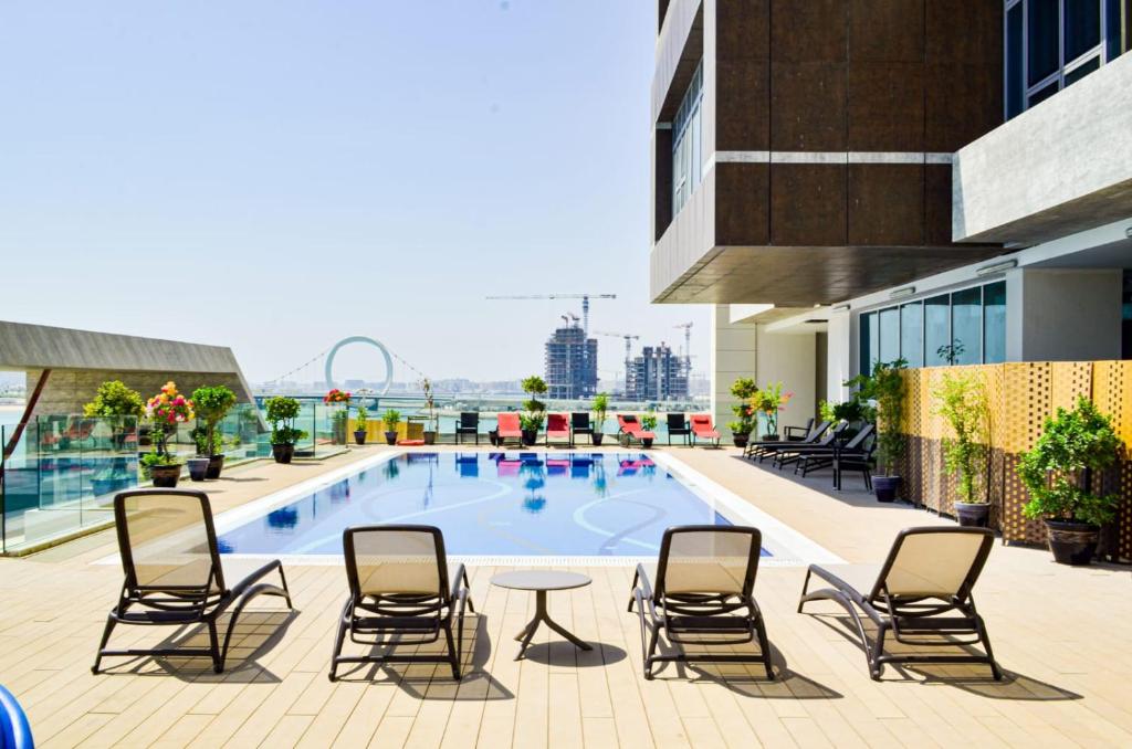 a pool on the roof of a building with chairs and a table at Waterfront Hotel Apartment in Lusail
