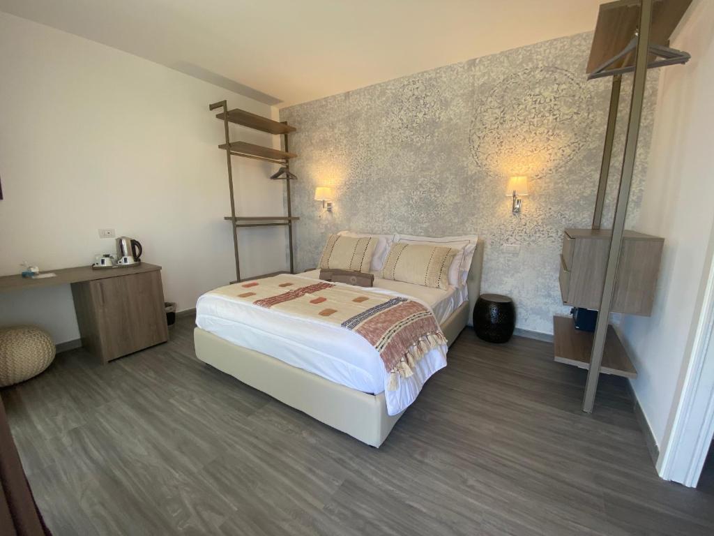 a bedroom with a white bed and a wall at Suimi's Hotel in Villasimius