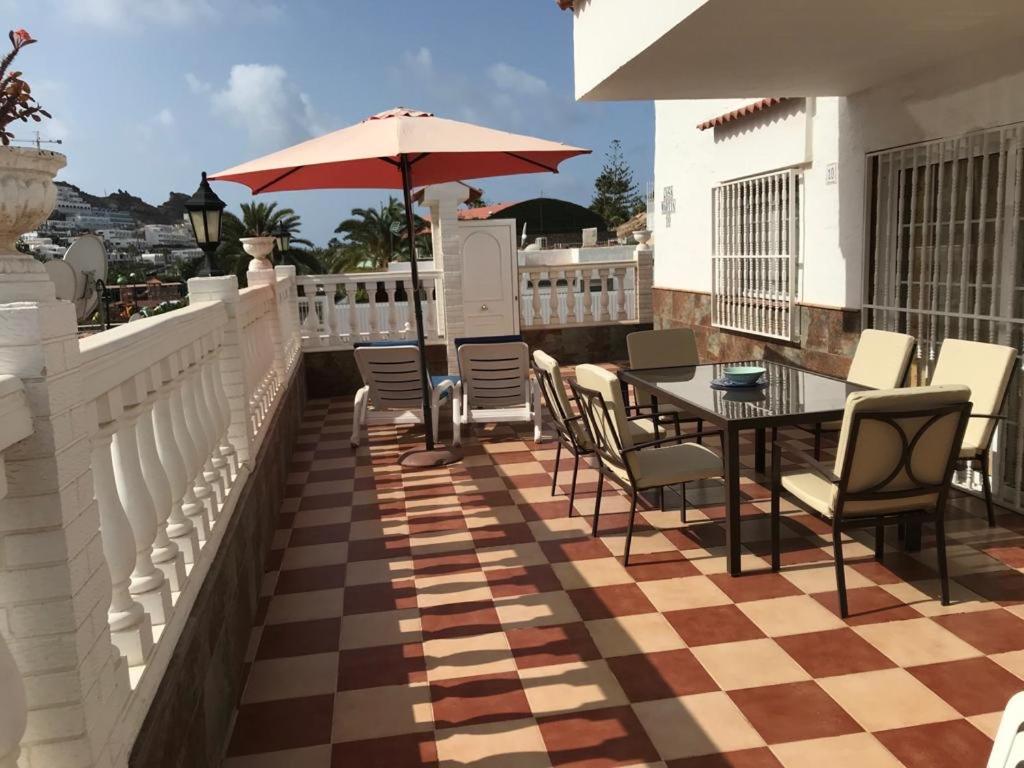 eine Terrasse mit einem Tisch, Stühlen und einem Sonnenschirm in der Unterkunft Bungalow Isla Margarita in Puerto Rico de Gran Canaria