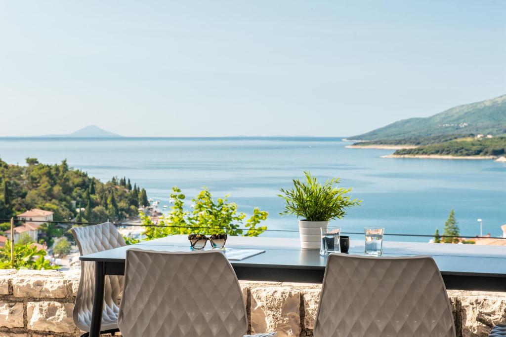 einen Tisch und Stühle mit Blick auf das Wasser in der Unterkunft Apartments Zulijani House Helis B1 & B6 in Rabac