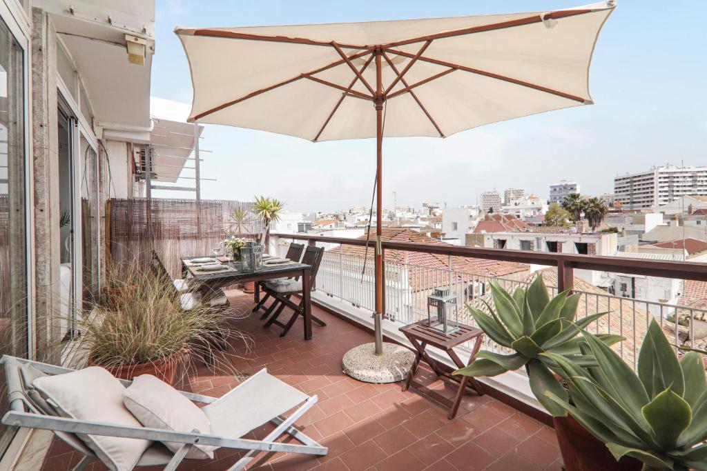 a patio with a table and an umbrella on a balcony at Panoramic Faro Apartment in Faro