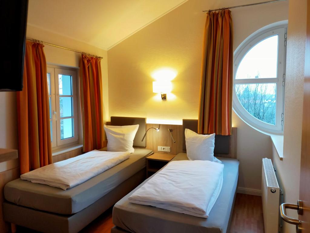 two beds in a room with a window at Hotel Xtra Gleis in Hörstel