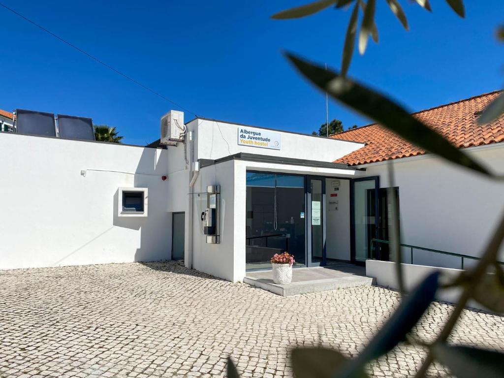 - un bâtiment blanc avec une porte ornée d'un vase de fleurs dans l'établissement Albergue da Juventude, à Tancos