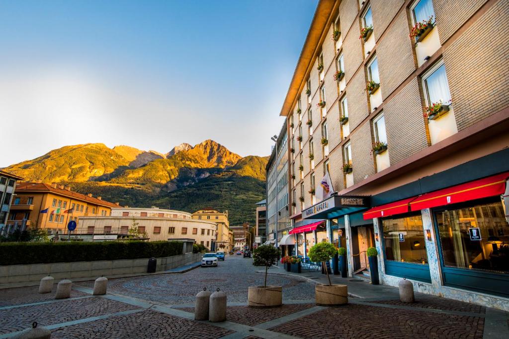 een stadsstraat met gebouwen en bergen op de achtergrond bij Duca D'Aosta Hotel in Aosta