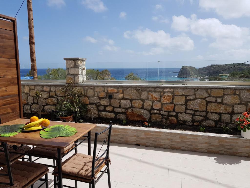 una mesa y sillas en un patio con una pared de piedra en Galazia Thea Apartments, en Archangelos