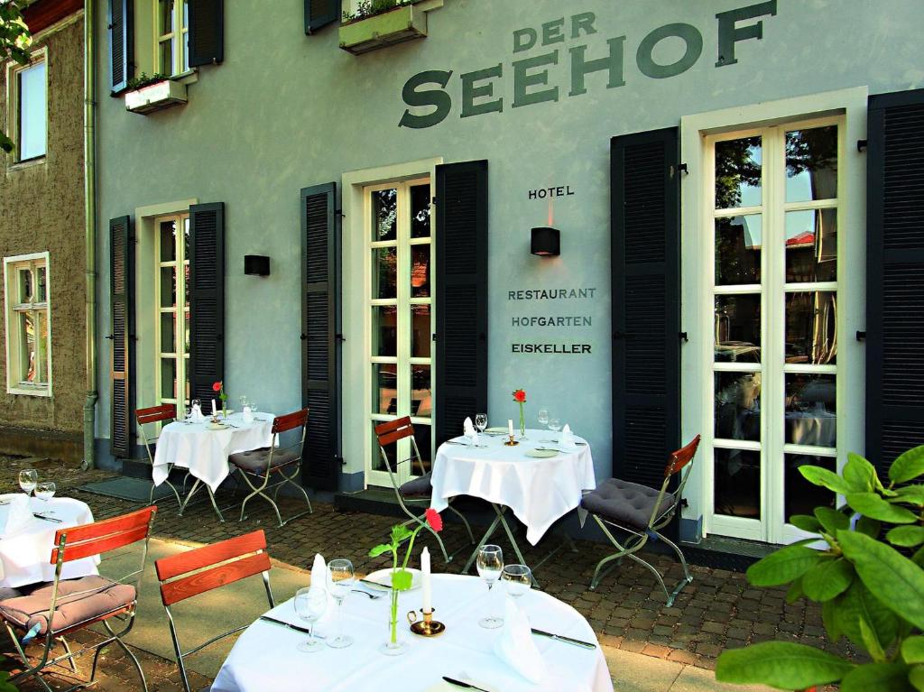 a restaurant with tables and chairs in front of a building at Der Seehof Rheinsberg in Rheinsberg