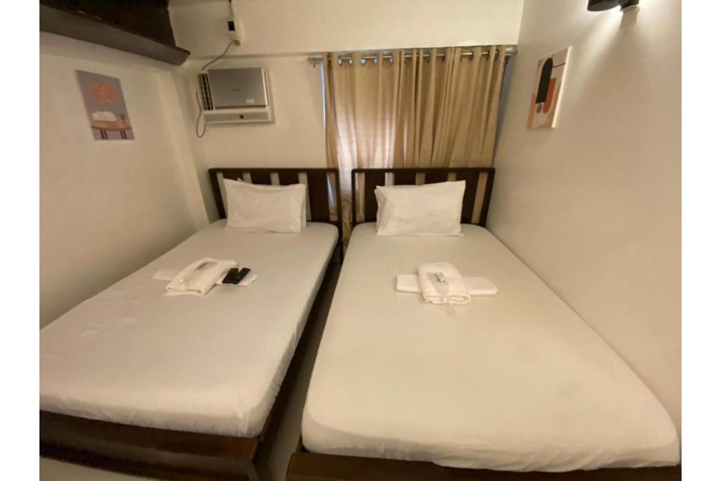 Dos camas en una habitación pequeña con sábanas blancas. en E Relaxed Haven Transient House, en Manila