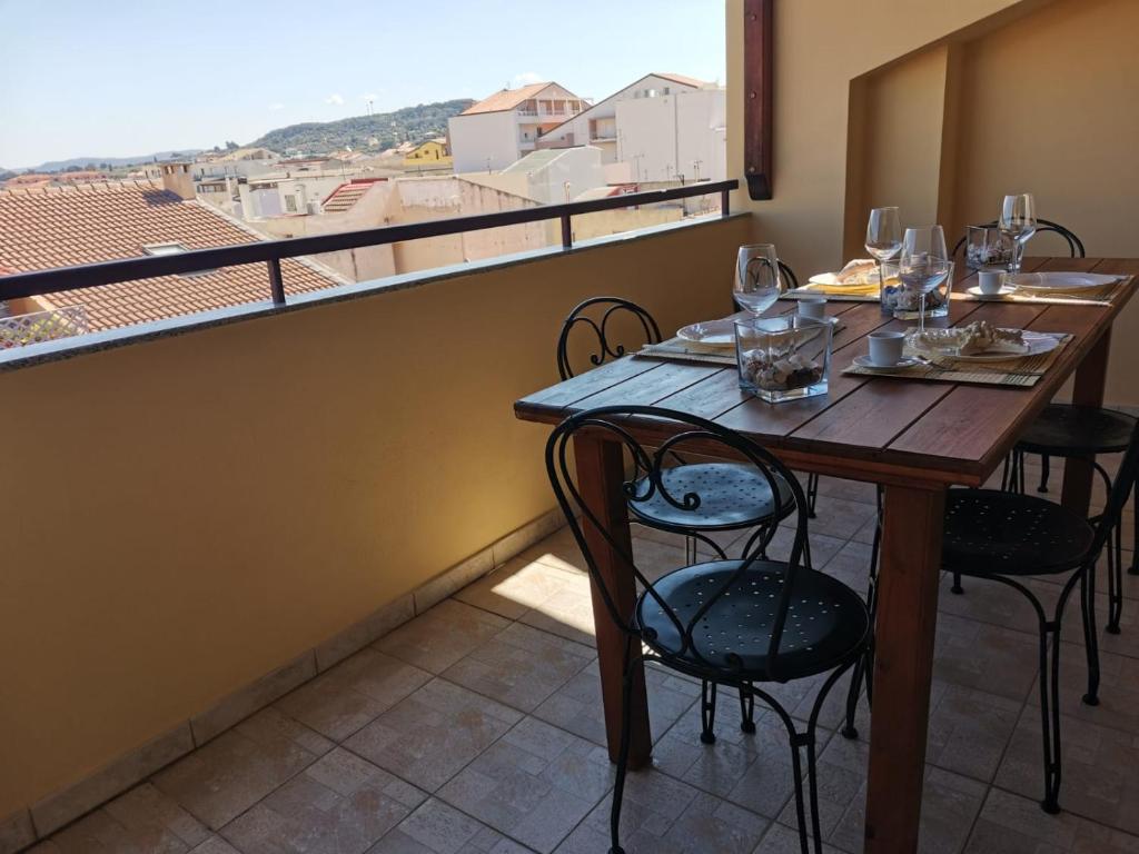 a table with chairs and wine glasses on a balcony at Satta 81 in Alghero
