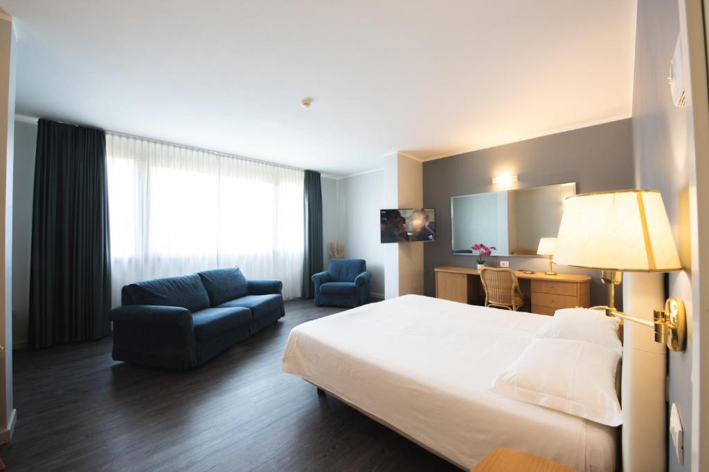 a hotel room with a large bed and a chair at Hotel Ristorante Primavera in Godega di SantʼUrbano