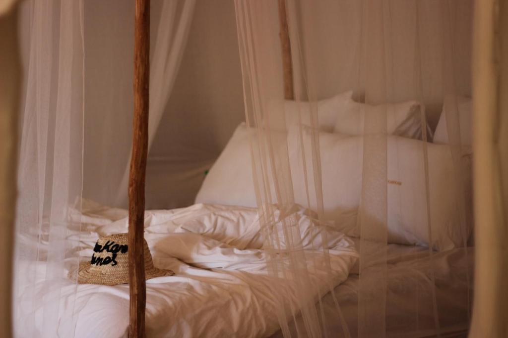 a bed with white sheets and a sign on it at Kam Kam Dunes in Merzouga