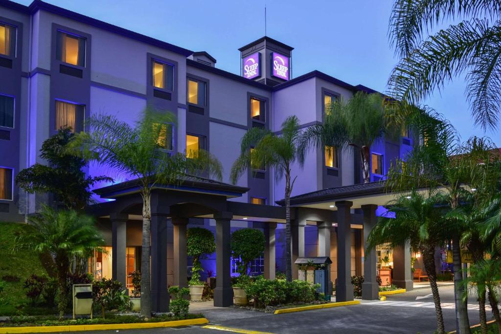 a hotel with a clock tower on top of it at Sleep Inn Hotel Paseo Las Damas in San José