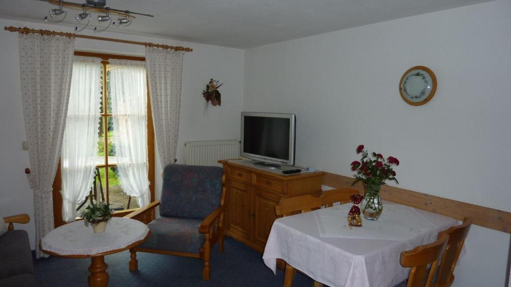 ein Wohnzimmer mit Fernseher und Tisch und Stühlen in der Unterkunft Fewo Ellen in Schönau am Königssee