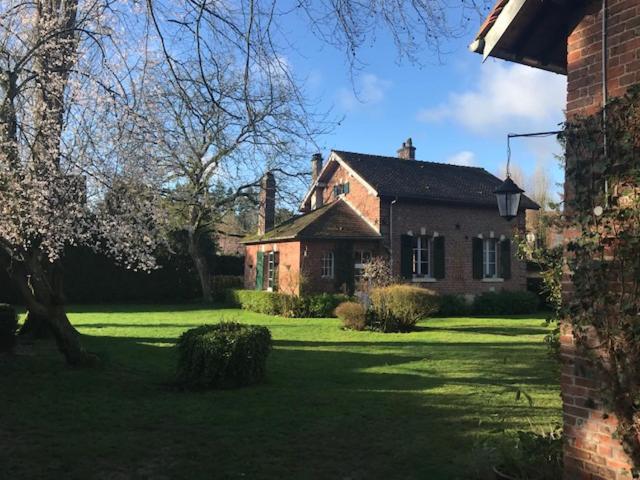 une ancienne maison en briques dans un champ d'herbe dans l'établissement La Maison des trois forêts, à Ermenonville