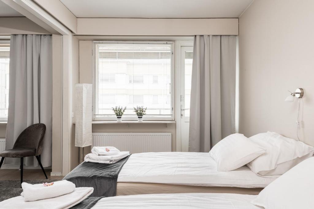 a bedroom with two beds and a chair and a window at Apartments Borg Antinkatu in Pori