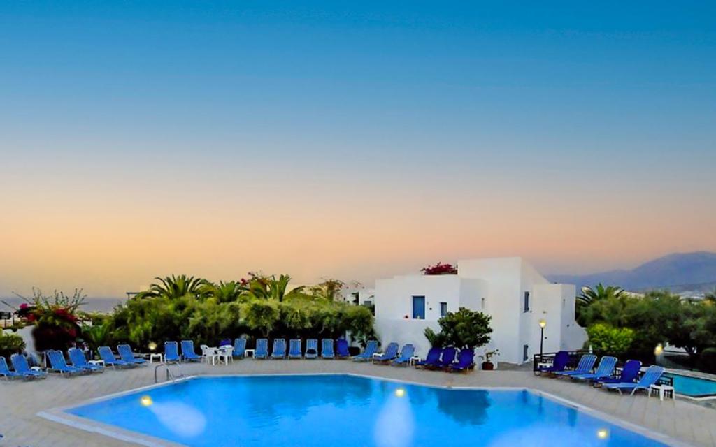 una gran piscina con sillas azules y un edificio en Palatia Village Hotel Apartments, en Hersonissos
