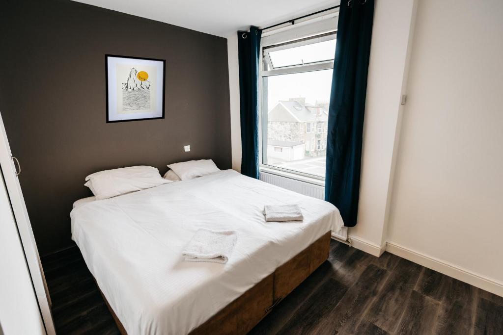 a bedroom with a bed with white sheets and a window at Mordon Bar and Lodge in Newquay