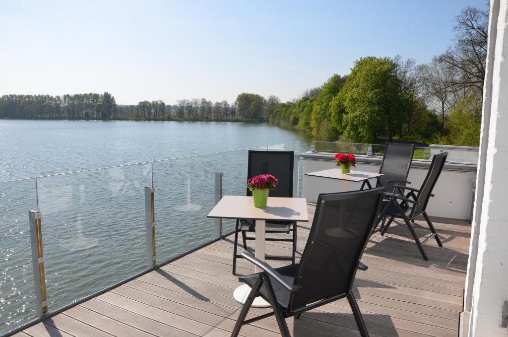 two tables and chairs on a deck next to the water at Vijverhuis in Ieper