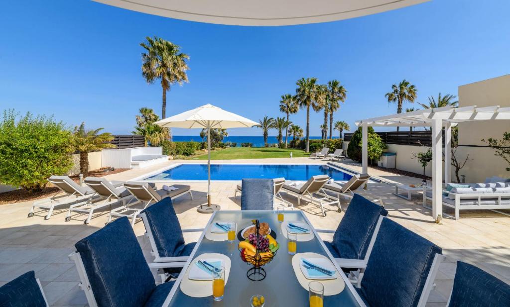 eine Terrasse mit einem Tisch und Stühlen sowie einem Pool in der Unterkunft Royal Beachfront Villa in Protaras