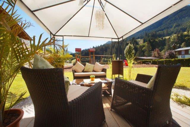 a patio area with chairs, tables and umbrellas at Hotel Austria in Saalbach-Hinterglemm