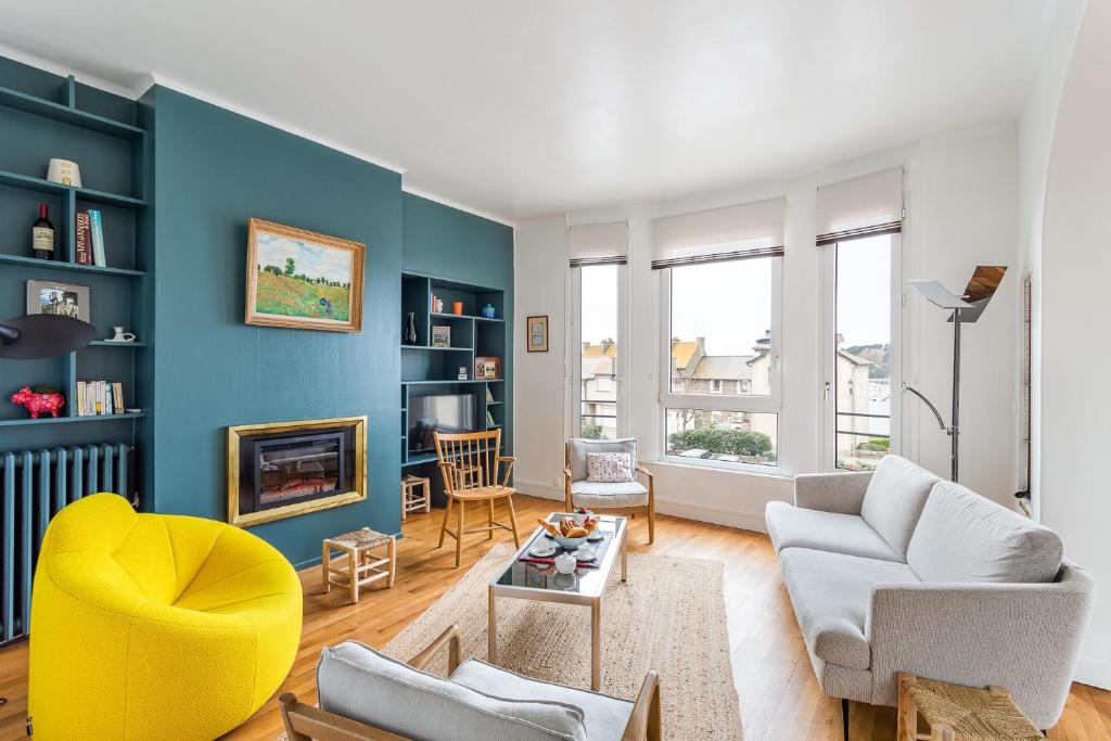 un salon avec des murs bleus et une chaise jaune dans l'établissement Le Hauturier - appartement de standing avec vue mer, à Saint-Malo