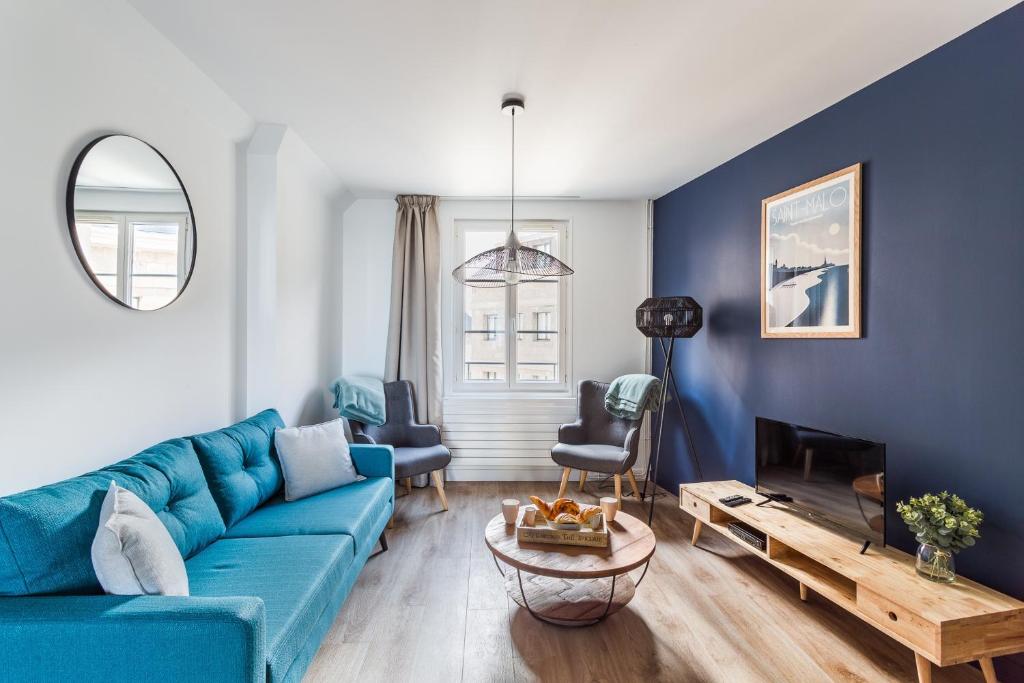 a living room with a blue couch and a table at Le Cap Cézembre - Intra-Muros Saint-Malo in Saint Malo