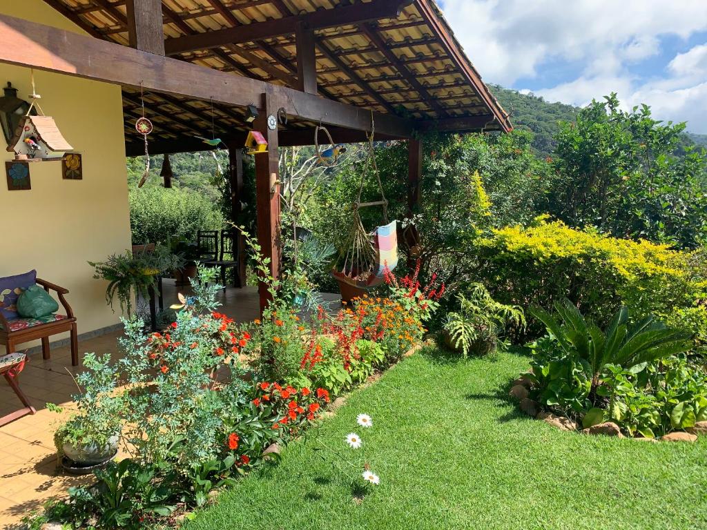 un giardino con fiori colorati e un pergolato di Vale das Estrelas - vale das videiras - araras a Petrópolis