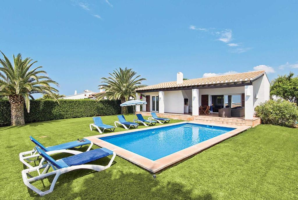 a yard with a swimming pool with chairs and a house at Sonrisa Binibeca Menorca in Binibeca