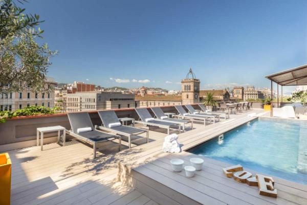 a row of lounge chairs and a swimming pool on a building at Enjoybcn Miro Apartments in Barcelona