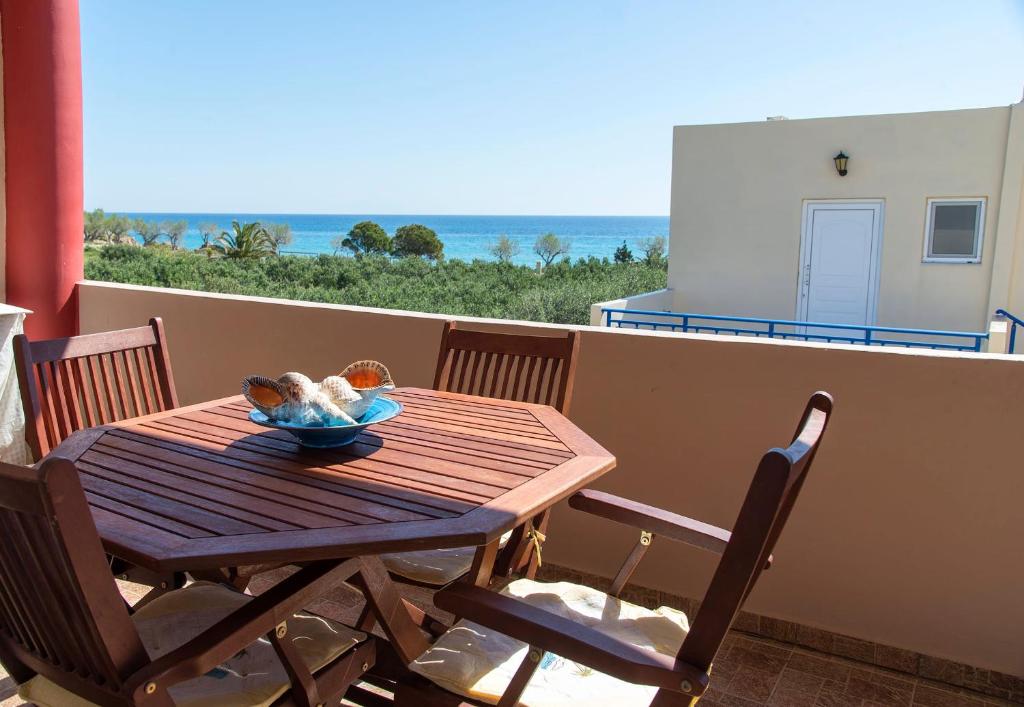 un tavolo in legno su un balcone con vista sull'oceano di Coastal Charm-Getaway to Artichoke's Seaside Oasis a Xerokampos