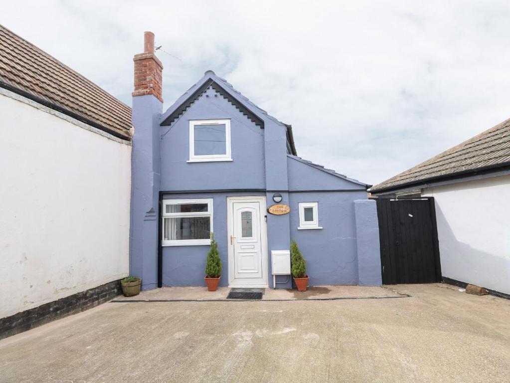 a blue house with a white door in a driveway at Oar Cottage in Mablethorpe