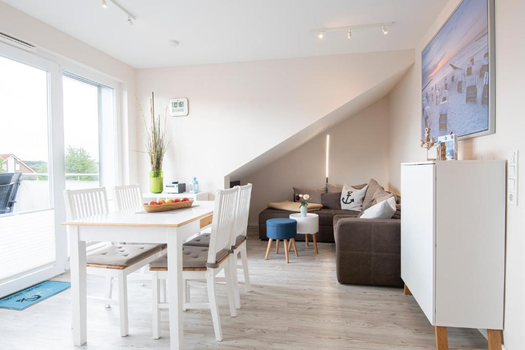 uma cozinha e sala de estar com uma mesa branca e cadeiras em Ostseequartier Ankerplatz em Kellenhusen