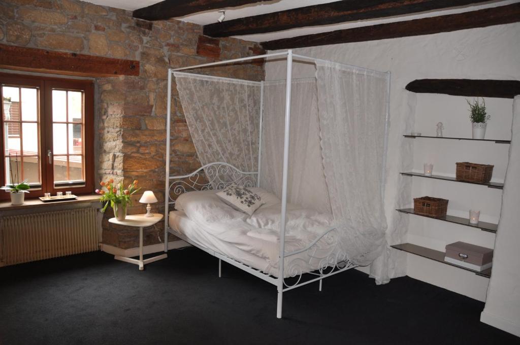 a swinging bed in a room with a brick wall at Maison de Charme "Le Moulin d'Hagenthal" - Chambre Romantique in Hagenthal-le-Bas