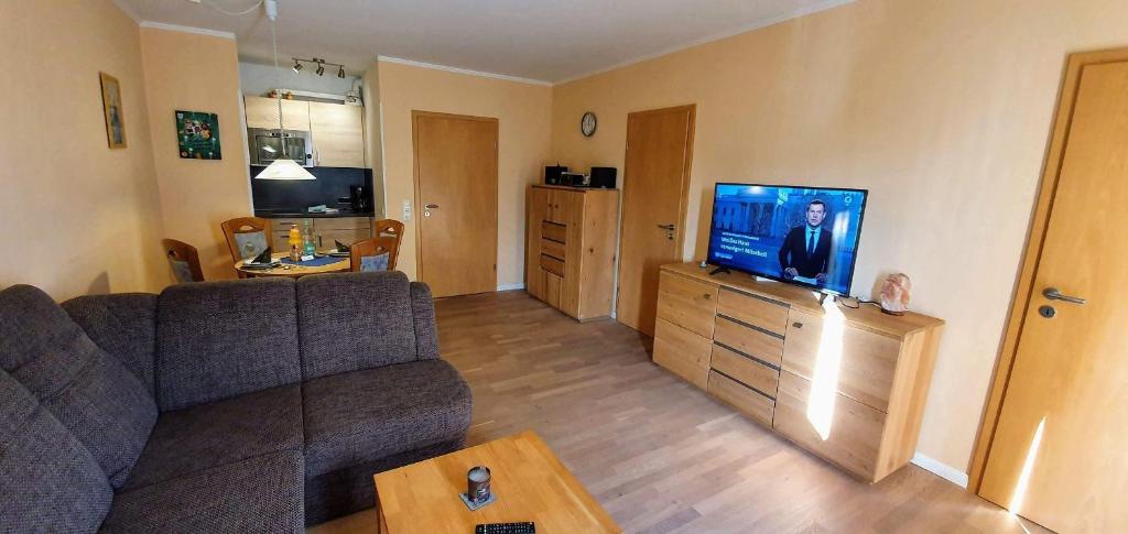 een woonkamer met een bank en een flatscreen-tv bij FeWo-Nordsee-Whg-11 in Sankt Peter-Ording
