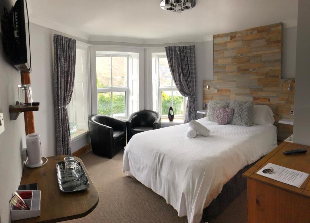 a hotel room with a bed and a desk and chairs at Alpine Lodge Guest House in Llanberis