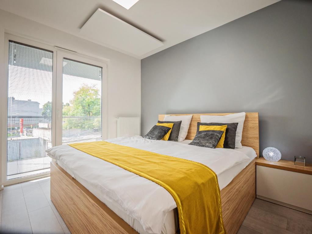 a bedroom with a large bed with a yellow blanket on it at Apartamenty Homely Place Centrum in Poznań