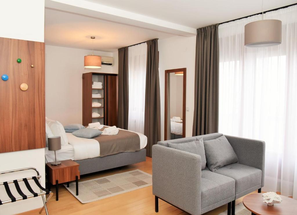 een slaapkamer met een bed, een bank en een stoel bij MILA in Vrnjačka Banja
