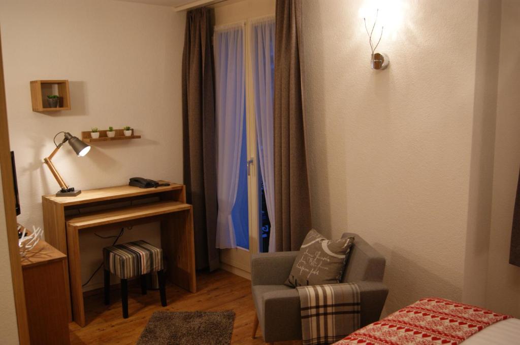 a room with a bed and a chair and a desk at Hotel Schweizerhof in Engelberg