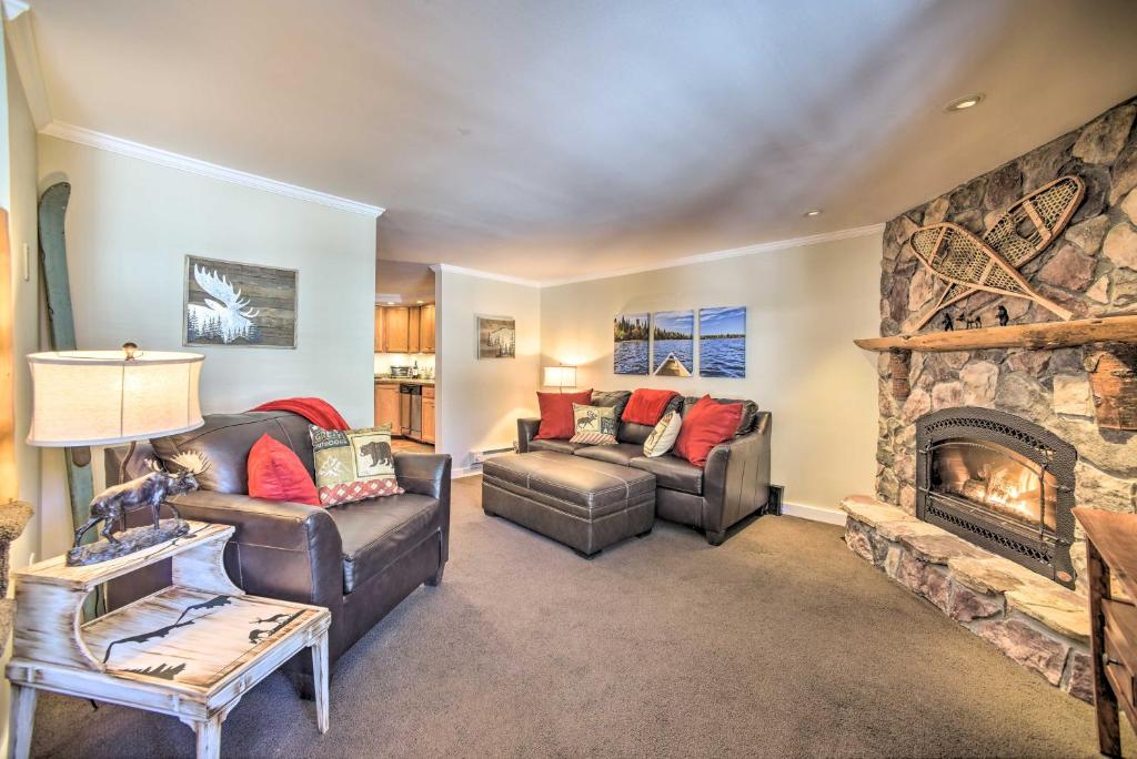 una sala de estar con 2 sofás y una chimenea de piedra. en Cozy Condo by Mirror Lake, 1 Block to Downtown!, en Lake Placid