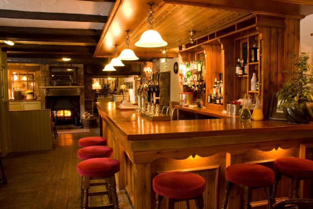 a bar with red stools in a restaurant at The Tankerville Arms in Eglingham