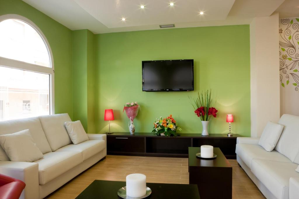 a living room with a couch and a tv on a green wall at Hotel Quino in Guardamar del Segura