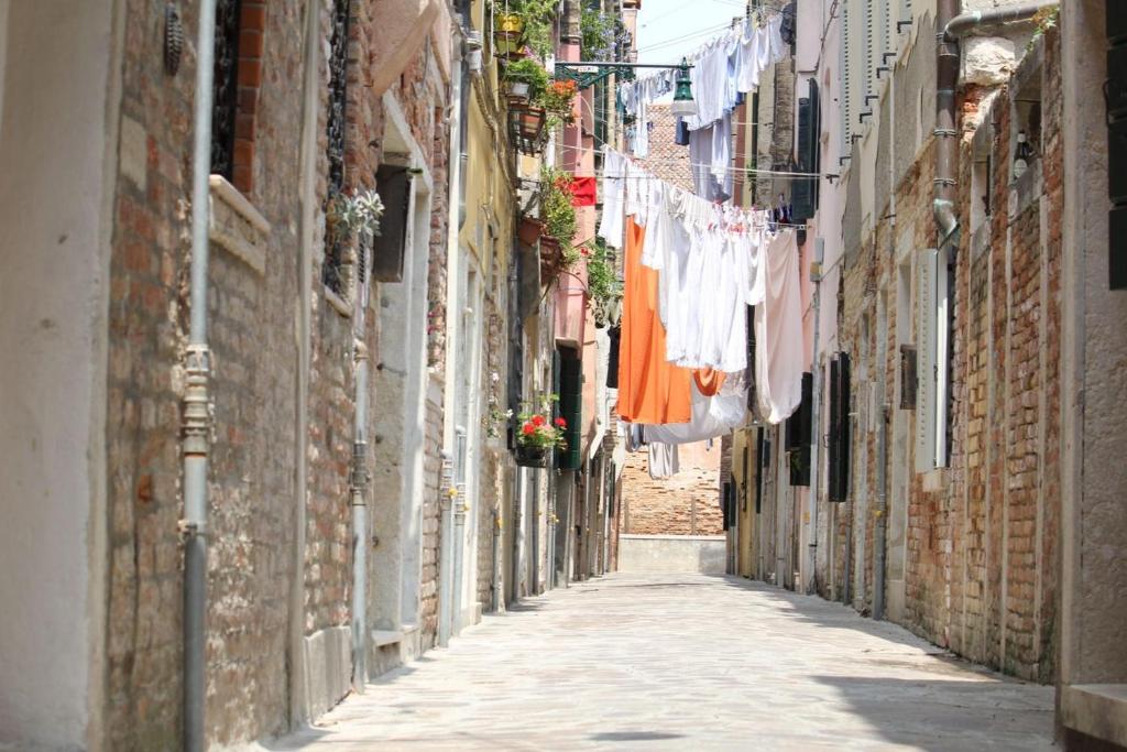 an alley with clothes drying on a clothes line at Veneziacentopercento Rooms in Venice
