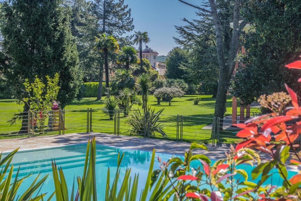 a garden with a swimming pool and a park at Residence Oasi in Manerba del Garda