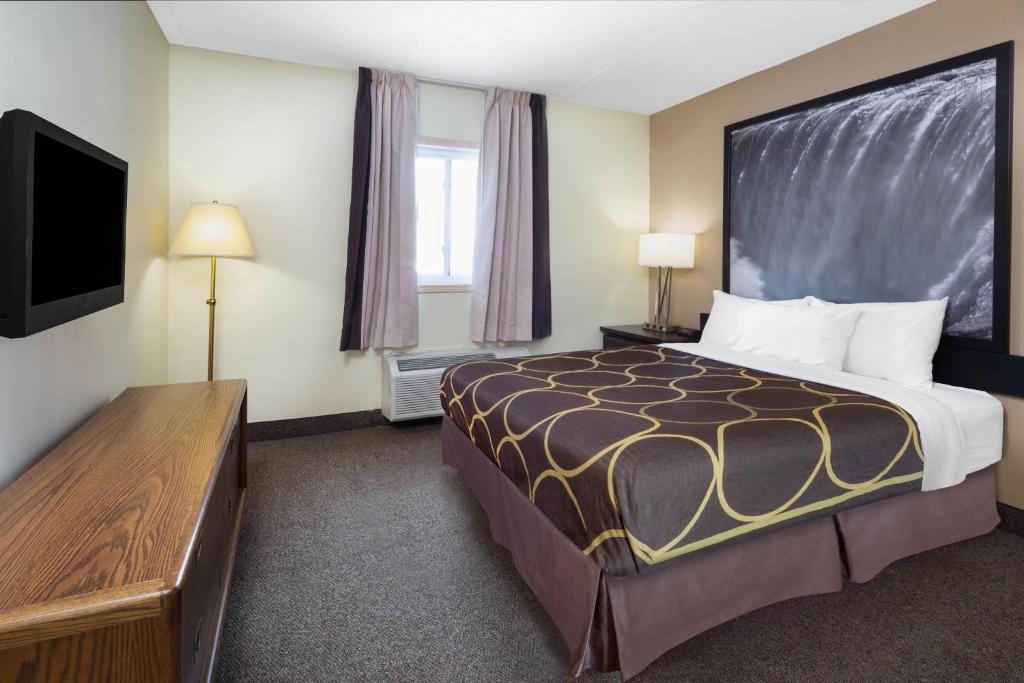 a hotel room with a bed and a flat screen tv at Super 8 by Wyndham Niagara Falls by the Falls in Niagara Falls