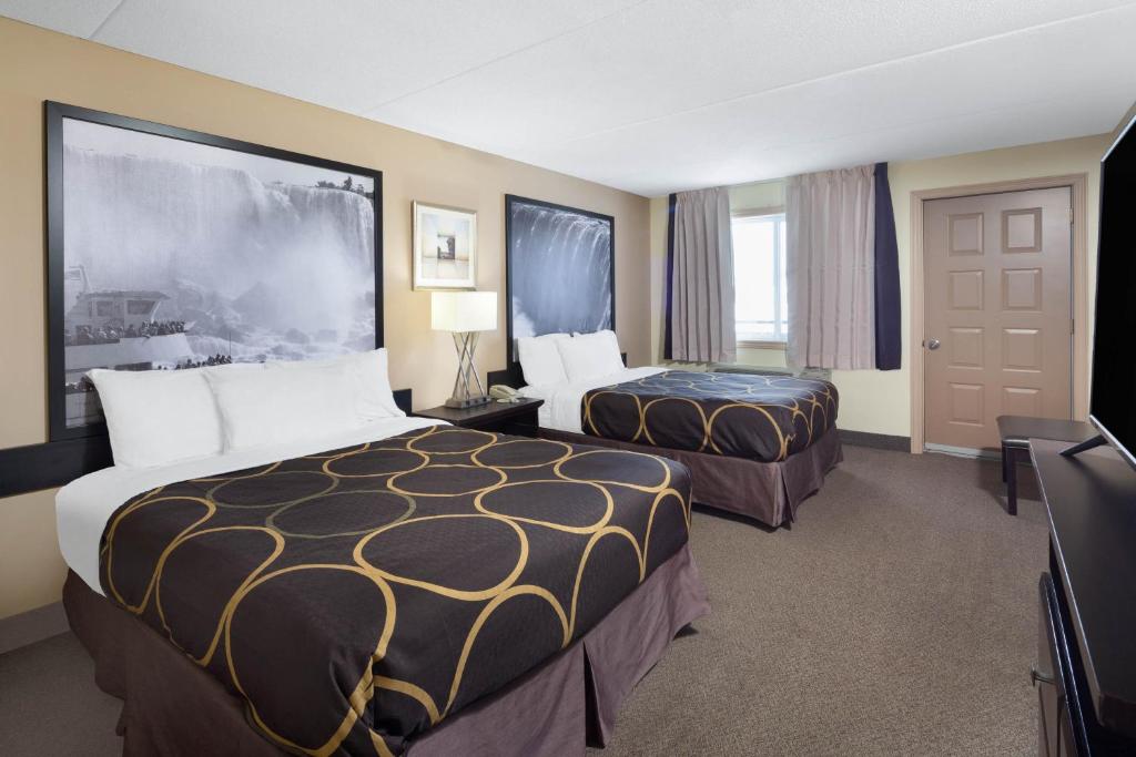 a hotel room with two beds and a television at Super 8 by Wyndham Niagara Falls by the Falls in Niagara Falls