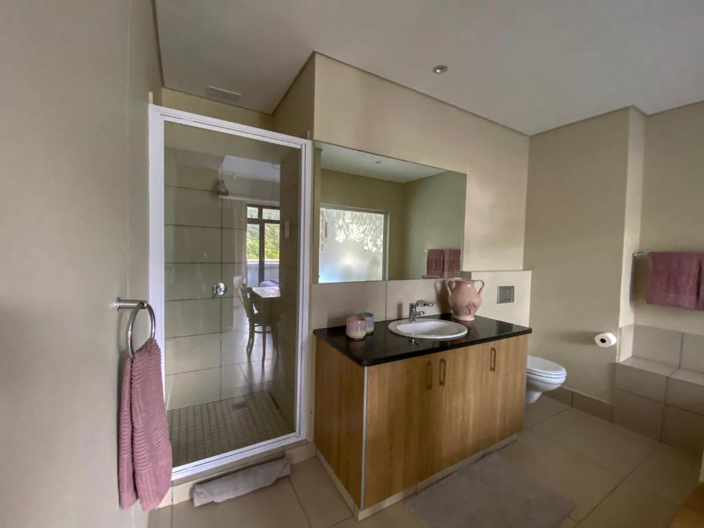 a bathroom with a sink and a shower with a mirror at 504 The HeroldsBay in Herolds Bay