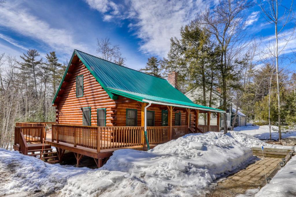 a log cabin with a green roof in the snow at Moose Cabin in Bridgton