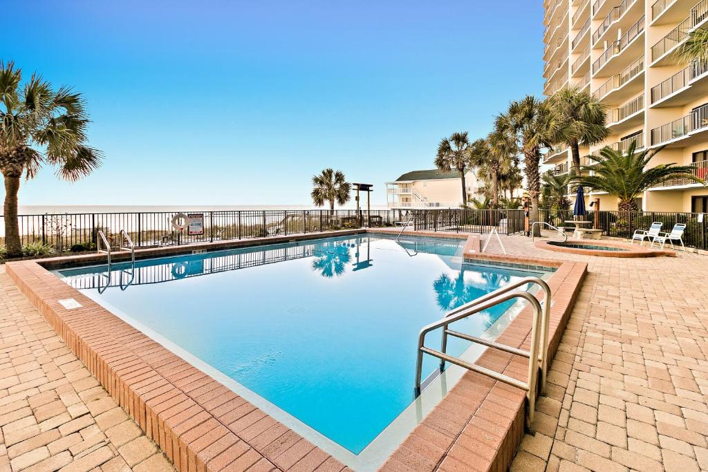 a swimming pool with palm trees and a building at The Commodore in Panama City Beach