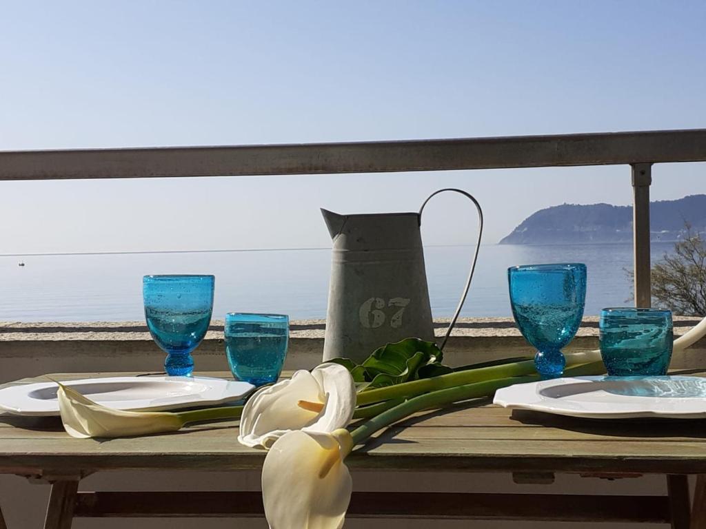 une table avec des assiettes, des verres bleus et une fleur dans l'établissement Cadorna Fronte Mare, à Alassio